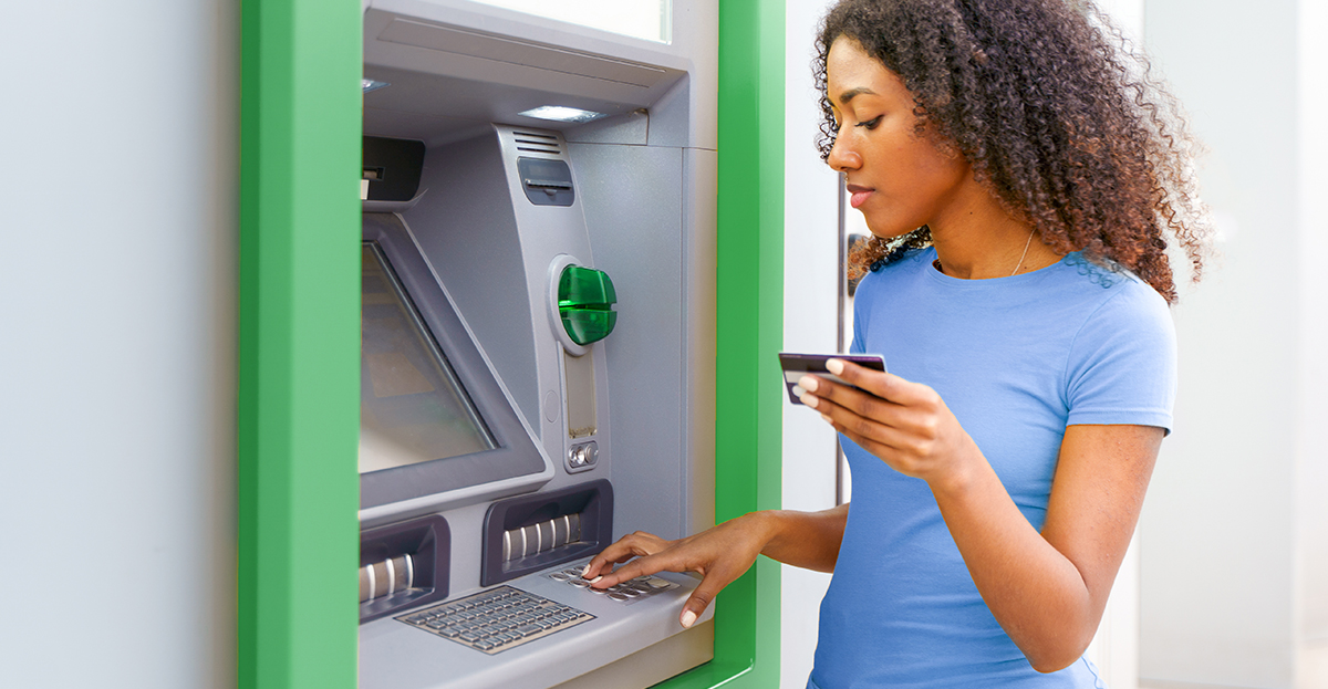 woman standing by atm with card in hand